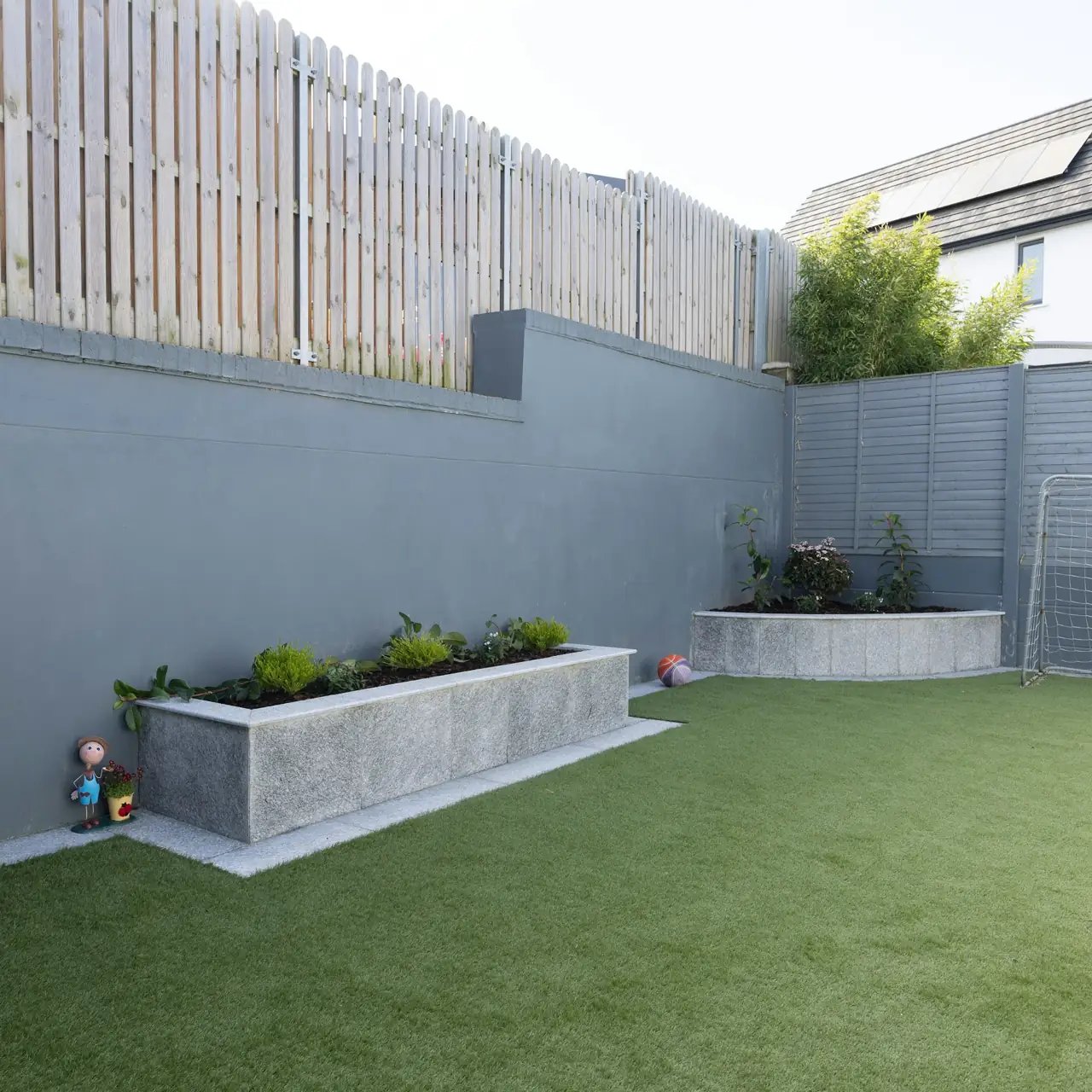 Backyard with artificial grass and a concrete planter